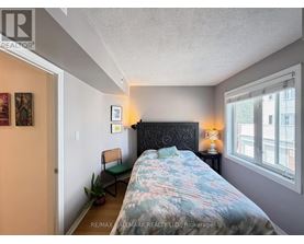 A bedroom with a bed, chair, and lamp.