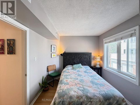 A bedroom with a bed, chair, and lamp.