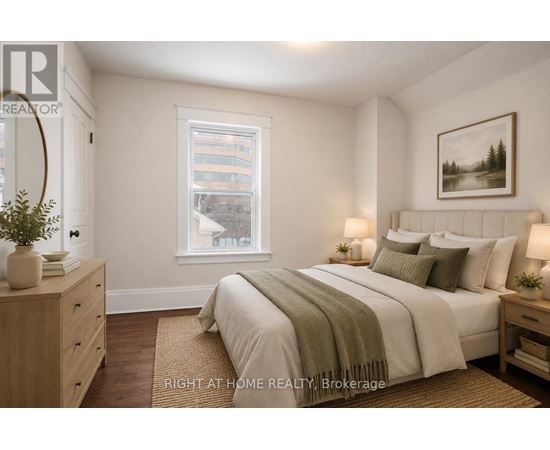 A well-lit bedroom with a large bed, a nightstand, and a window.