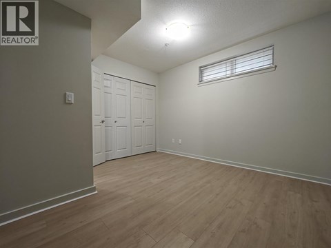 A bedroom with a white door and a window with blinds.