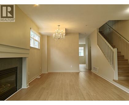 A large, empty living room with a fireplace and a chandelier.