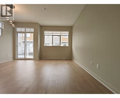 A spacious room with wooden flooring and large windows.