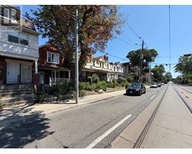A street view with houses on both sides and a car driving down the road.