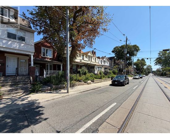 A street view with houses on both sides and a car driving down the road.