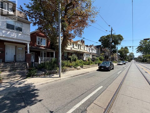 A street view with houses on both sides and a car driving down the road.