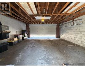 A spacious garage with a brick wall and wooden beams on the ceiling.