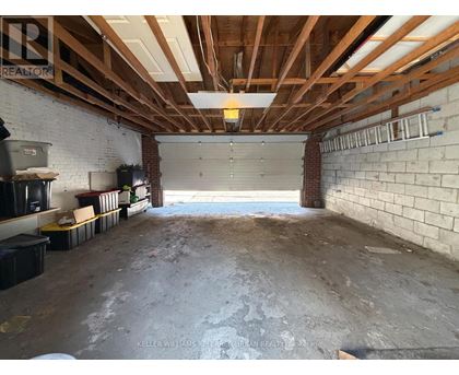 A spacious garage with a brick wall and wooden beams on the ceiling.