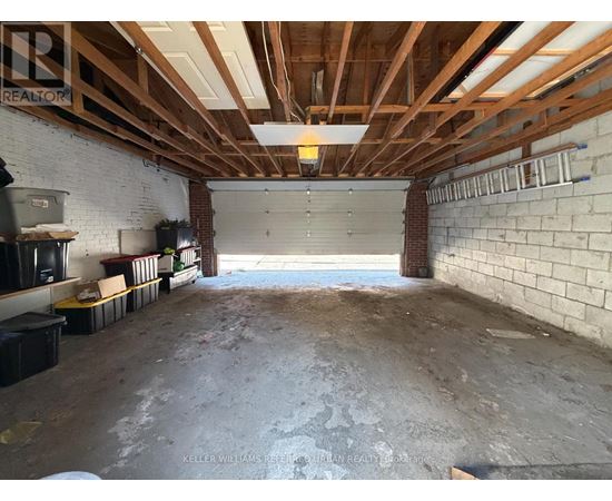 A spacious garage with a brick wall and wooden beams on the ceiling.
