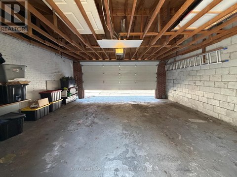 A spacious garage with a brick wall and wooden beams on the ceiling.