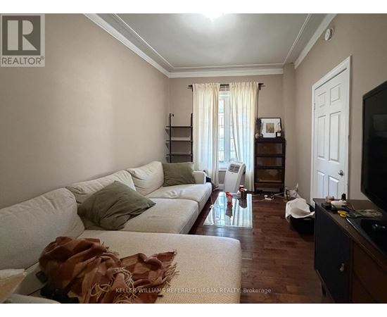 A living room with a white couch and a brown throw on it.