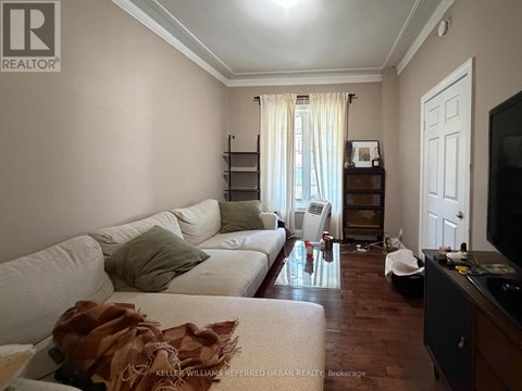 A living room with a white couch and a brown throw on it.