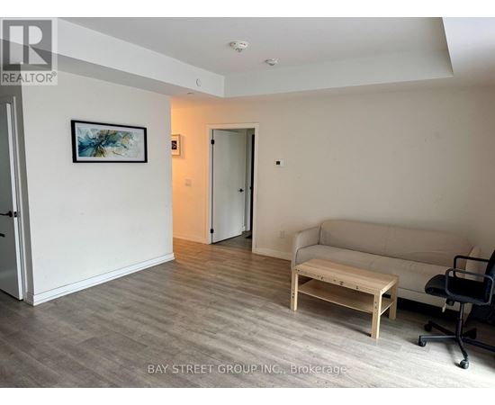A living room with a couch, coffee table, and a painting on the wall.