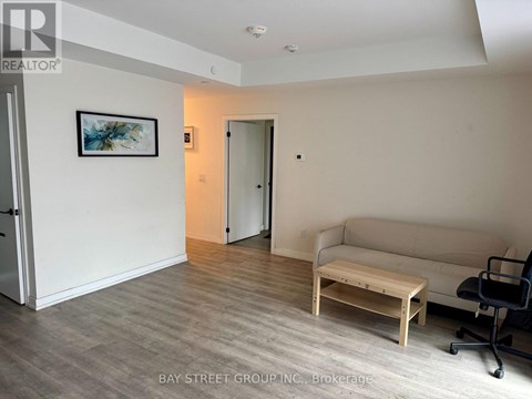 A living room with a couch, coffee table, and a painting on the wall.