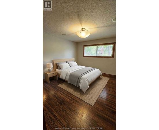 A bedroom with a bed, nightstand, and window.