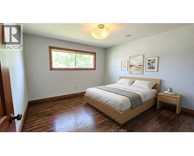 A bedroom with a bed, nightstand, and a window.