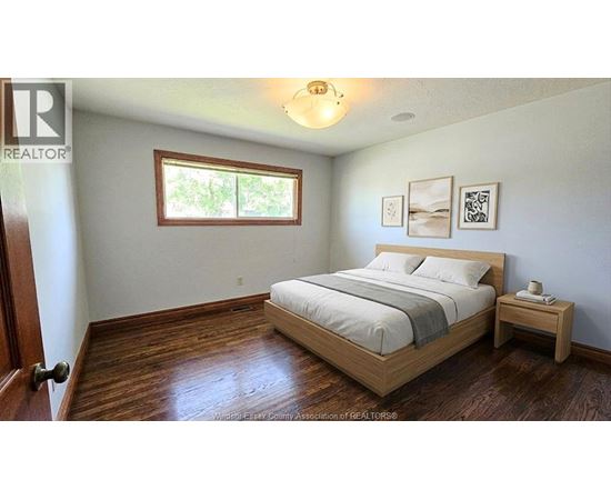 A bedroom with a bed, nightstand, and a window.