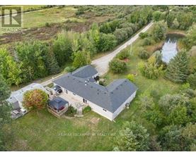 A bird's eye view of a house surrounded by trees and a pond.