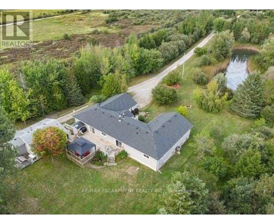 A bird's eye view of a house surrounded by trees and a pond.