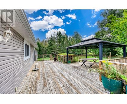 A wooden deck with a gazebo and potted plants.