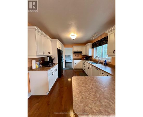A kitchen with white cabinets and a wooden floor.