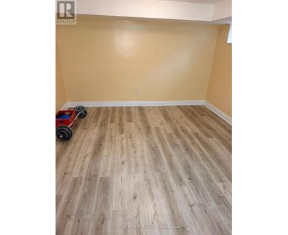 A room with wooden flooring and a red toy car on the floor.