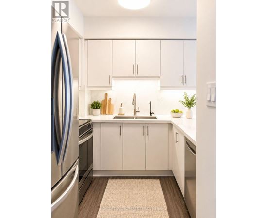 A modern kitchen with white cabinets and a wooden floor.