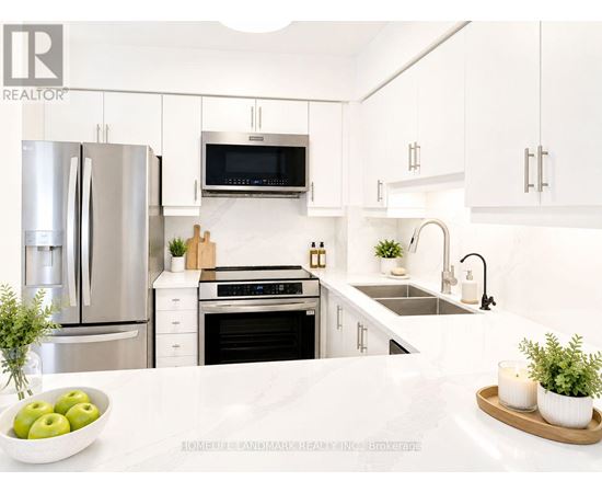A modern kitchen with a refrigerator, microwave, oven, and sink.