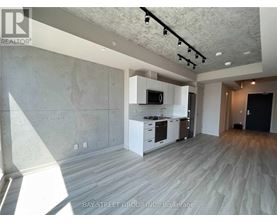 A spacious room with a kitchen area and a wood floor.