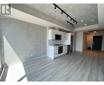 A spacious room with a kitchen area and a wood floor.