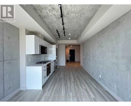 A modern kitchen with white cabinets and a wooden floor.