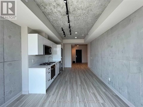 A modern kitchen with white cabinets and a wooden floor.