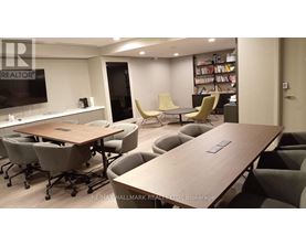 A conference room with a long table and chairs, a television, and a bookshelf filled with books.