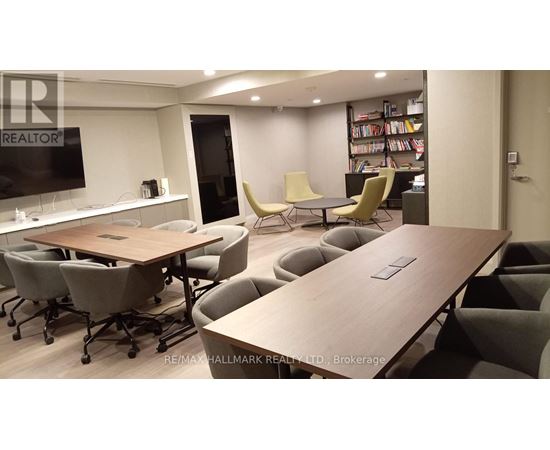 A conference room with a long table and chairs, a television, and a bookshelf filled with books.