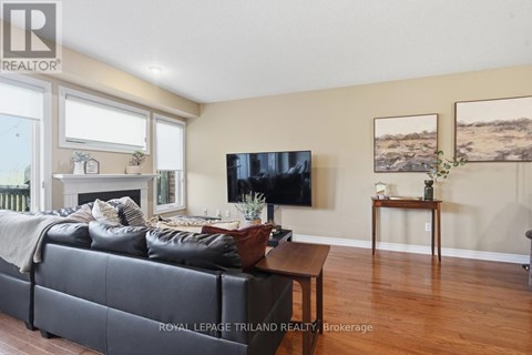 A living room with a black couch and a flat screen TV mounted on the wall.