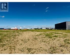 A field with buildings in the distance under a blue sky.