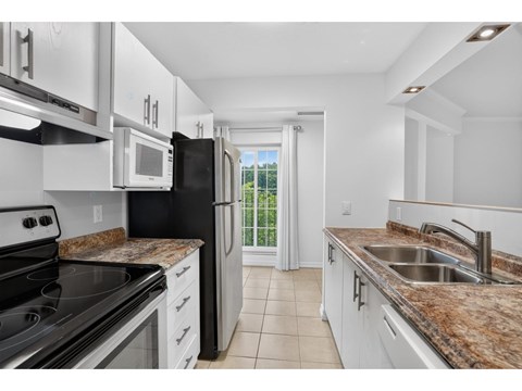 A kitchen with black appliances and granite countertops.