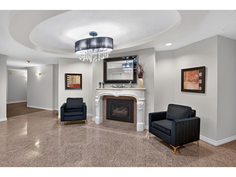 A living room with a fireplace and two chairs.
