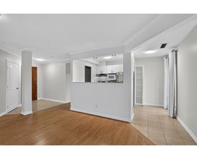 A spacious room with wooden flooring and white walls.