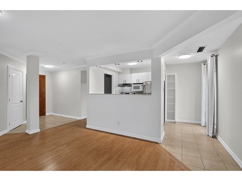 A spacious room with wooden flooring and white walls.