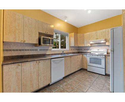 A kitchen with wooden cabinets and a white dishwasher.