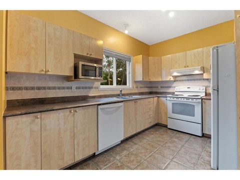 A kitchen with wooden cabinets and a white dishwasher.