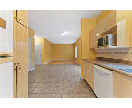 A kitchen with wooden cabinets and a tiled floor.