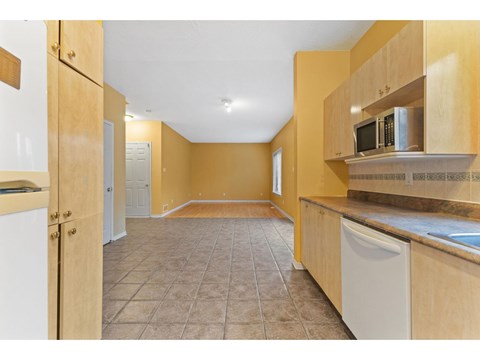 A kitchen with wooden cabinets and a tiled floor.