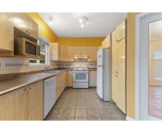 A kitchen with wooden cabinets and a tiled floor.