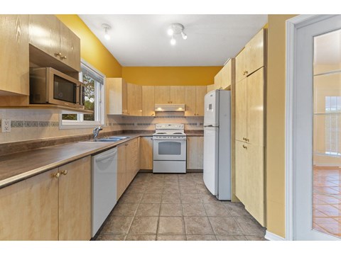 A kitchen with wooden cabinets and a tiled floor.