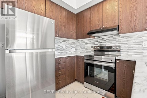 A modern kitchen with wooden cabinets and a stainless steel refrigerator.