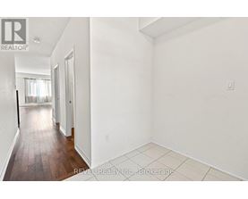 A white room with a wooden floor and a door leading to another room.