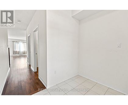 A white room with a wooden floor and a door leading to another room.