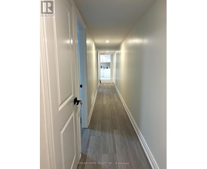 A hallway with wood flooring and white walls.