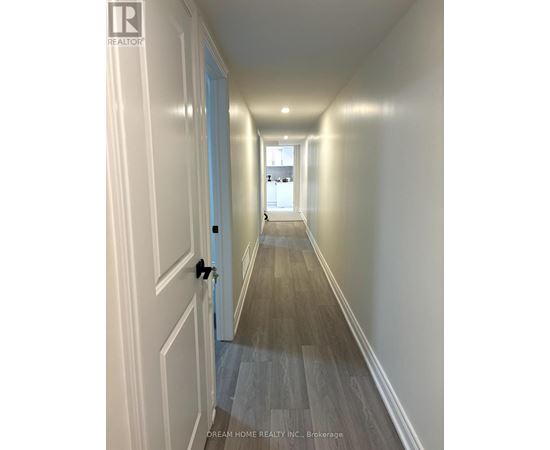 A hallway with wood flooring and white walls.